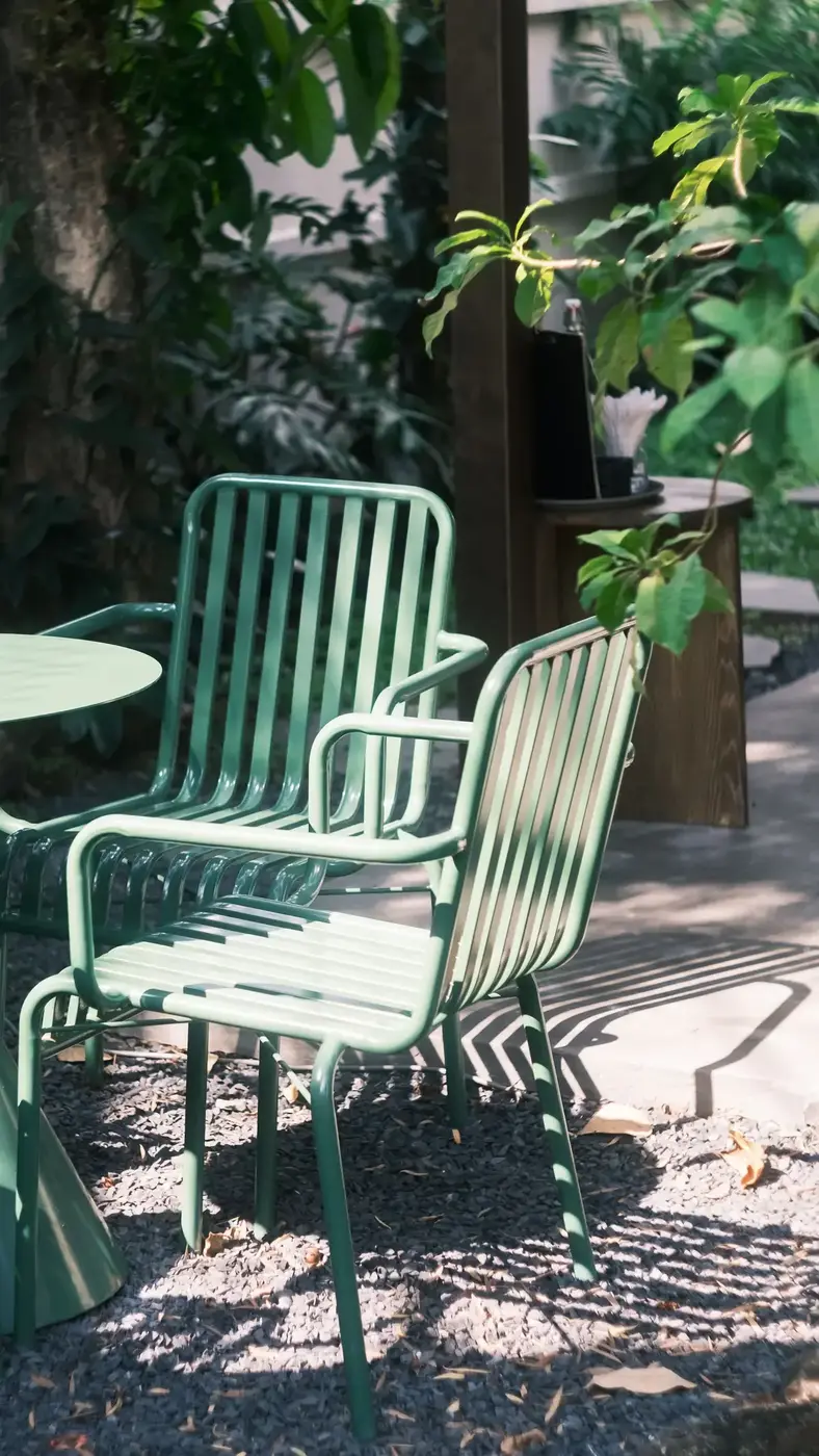 Two green metal chairs on a sunlit patio