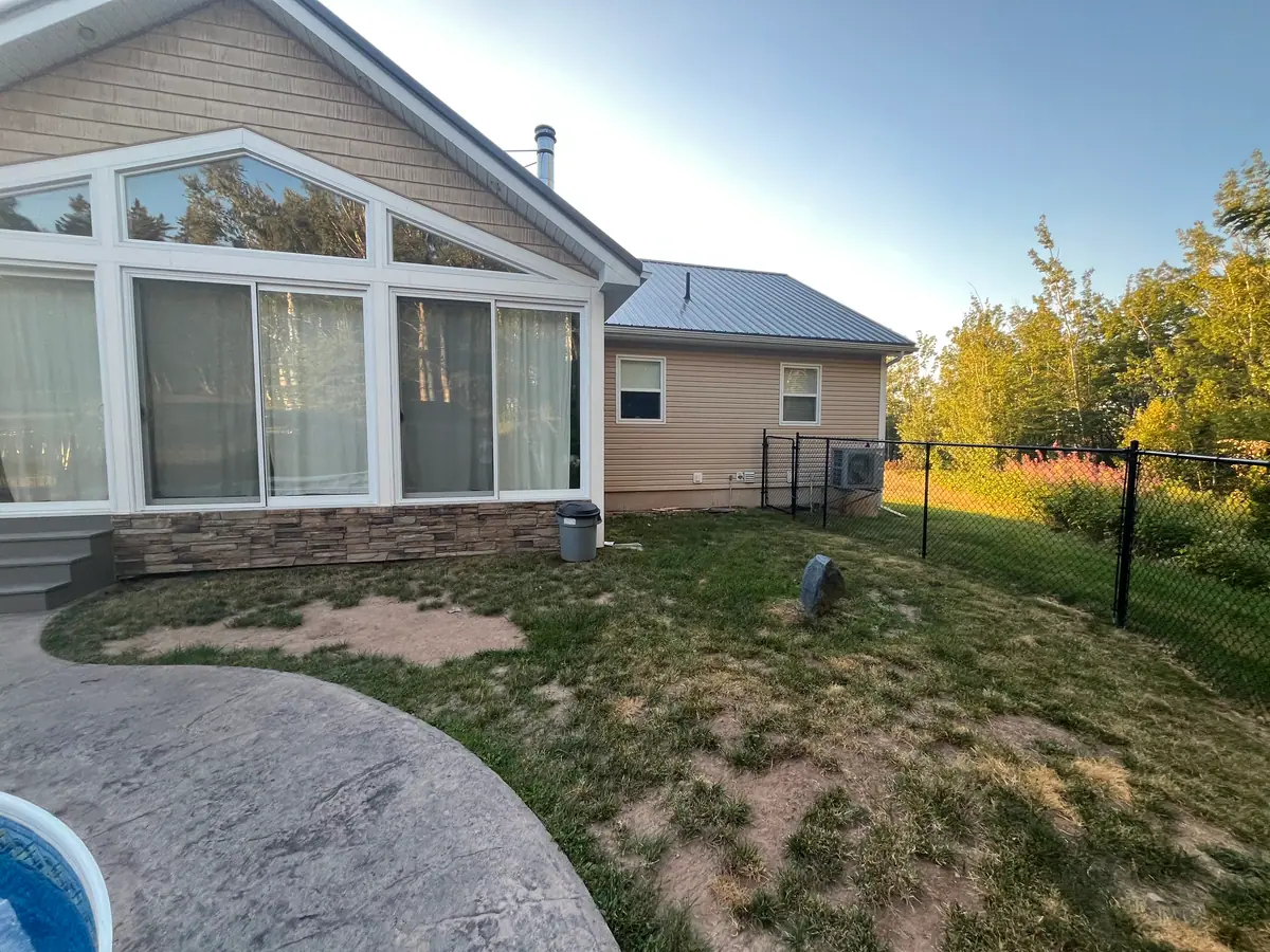 Before: patchy, worn grass between a stamped-concrete pool deck and a chain-link fence behind a sunroom